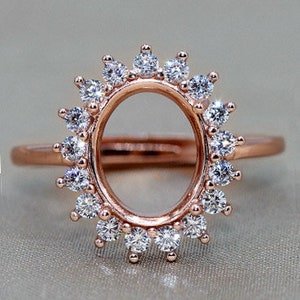 Pode incluir: Uma configuração de anel de ouro rosa com um halo de pequenos diamantes redondos. A configuração é projetada para segurar uma pedra central oval.