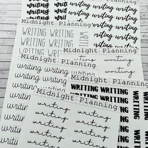 Puede incluir: Una hoja de papel adhesivo transparente con letras negras. Las pegatinas muestran las palabras "Midnight Planning" y "Writing" en diferentes fuentes y tamaños.
