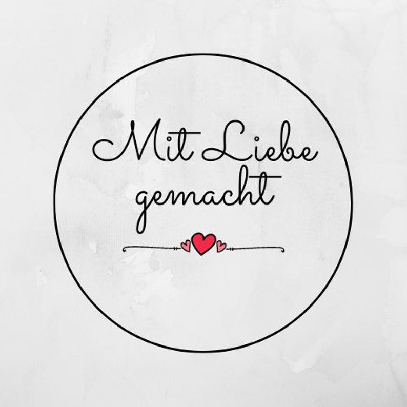 May include: A black and white circle with the text "Mit Liebe gemacht" in cursive script. Two small red hearts are above the text.