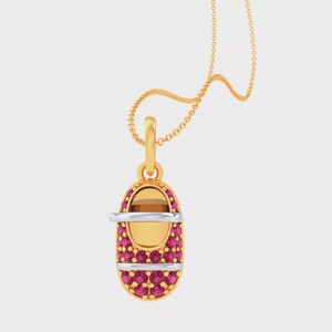 May include: A gold pendant shaped like a baby shoe suspended from a delicate gold chain. The shoe features a smooth gold toe and heel section, with the main body encrusted with numerous small, vibrant pink stones and a silver-toned strap across.
