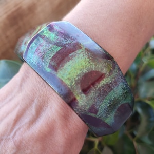 Pulsera ancha verde con aguas de mármol de colores en tonalidades violetas.