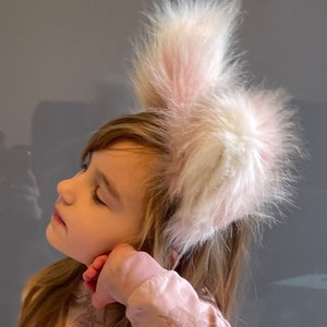 May include: A fluffy white and pink bunny ears headband. The ears are made of soft, faux fur and are attached to a headband. A fun accessory for Easter, cosplay, or themed parties.