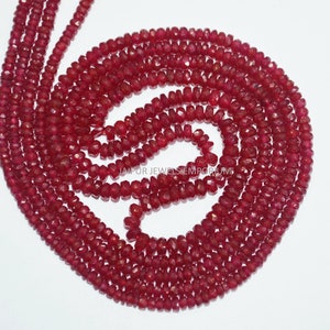 May include: A strand of deep red ruby beads, faceted and polished, arranged in a circular pattern. The beads are small and uniform in size, creating a smooth and elegant look.