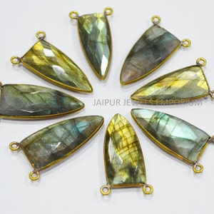 May include: Eight gold-toned metal gemstone pendants with a pointed, teardrop shape. The gemstones are iridescent labradorite with green, blue, and gold tones. Each pendant has two loops for attaching to jewelry.