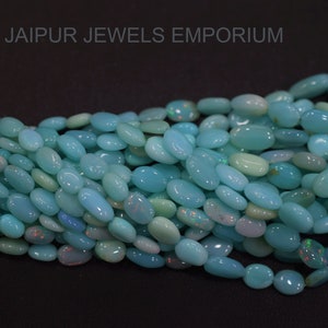 May include: A strand of oval-shaped turquoise blue opal beads. The beads are smooth and have a slight iridescent sheen.