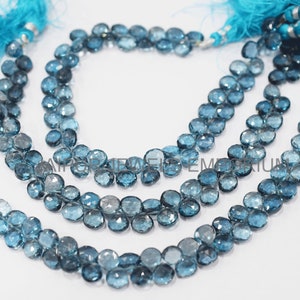 May include: A strand of blue topaz gemstone beads, with a tassel on each end. The beads are faceted and have a light blue colour.