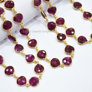 May include: A strand of ruby gemstone beads with gold accents. The beads are faceted and have a teardrop shape. The chain is made of gold metal.