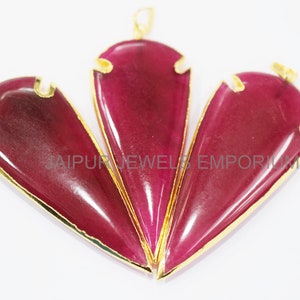 May include: Three gold-rimmed arrowhead pendants with a deep red, almost burgundy, color. The pendants are arranged in a triangle shape.