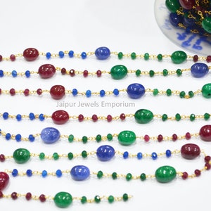 May include: A gold chain with red, green, and blue oval beads. The chain is made of small gold links and is interspersed with smaller round beads. The text "Jaipur Jewels Emporium" is visible in the image.