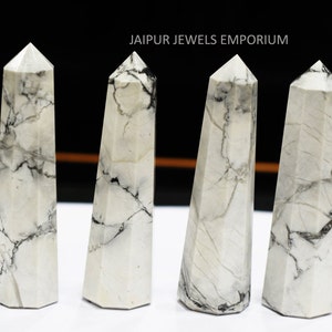 Può includere: Quattro punte di cristallo marmoree bianche e nere, ciascuna con una punta appuntita e una base esagonale. I cristalli sono disposti in fila su una superficie bianca. JAIPUR JEWELS EMPORIUM è scritto in testo nero nella parte superiore dell'immagine.