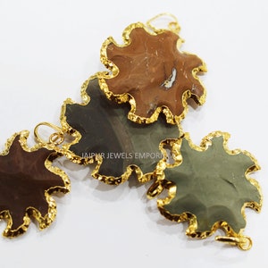 May include: Three gold-rimmed pendants with a starburst shape. The pendants are made of natural stone with brown, gray, and green colors. The pendants are for jewelry making.