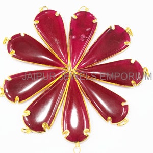 May include: Eight teardrop-shaped red gemstone pendants with gold-toned metal accents. The pendants are arranged in a circular pattern.