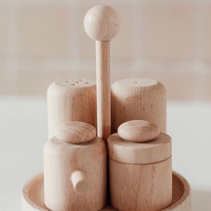 May include: A set of four wooden salt and pepper shakers with a wooden stand. The shakers are all the same size and shape, and they have a simple, minimalist design.
