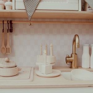 May include: A wooden toy kitchen playset with a gold faucet, a wooden pot with a lid, a wooden cake with candles, and two wooden milk bottles.