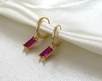 Puede incluir: Pendientes de aro dorados con una piedra preciosa rectangular rosa colgante.