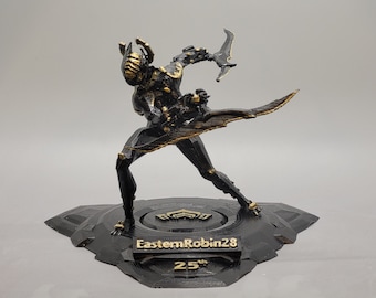 May include: A black and gold figurine of a character in a dynamic pose, holding a blade. The figurine is on a black base with the text "EasternRobin28" and "25th". The figure has a detailed design.