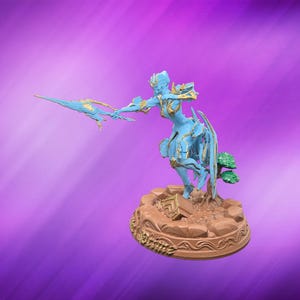 May include: A blue figurine of a warrior woman with gold accents, holding a spear. The figure is on a brown base with a tree and decorative elements. The background is a gradient of purple and pink.