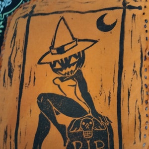 May include: A black and orange Halloween-themed illustration of a pumpkin with a witch's hat sitting on a tombstone with the words "RIP" on it. The background is orange.