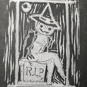 May include: A black and white linocut print featuring a figure with a pumpkin head wearing a pointed hat, sitting on a tombstone marked with the letters R.I.P. The scene is framed by a rectangular border with a crescent moon in the upper corner.