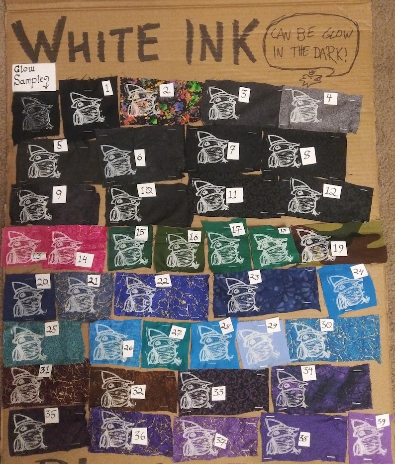 May include: A collection of fabric swatches with a white ink design of a frog wearing a hat. The swatches are numbered 1 through 39 and are arranged in rows on a cardboard background. The text "WHITE INK" is written at the top of the board. The text "CAN BE GLOW IN THE DARK!" is written in a speech bubble above the swatches. The text "Glow Samples" is written above the first row of swatches.