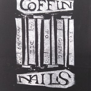 Può includere: Design grafico in bianco e nero con le parole "COFFIN NAILS" in alto e in basso. La frase "ANYWAY I'M GOING TO DIE" è stampata verticalmente al centro, con linee verticali. Il design ha un'estetica grunge.
