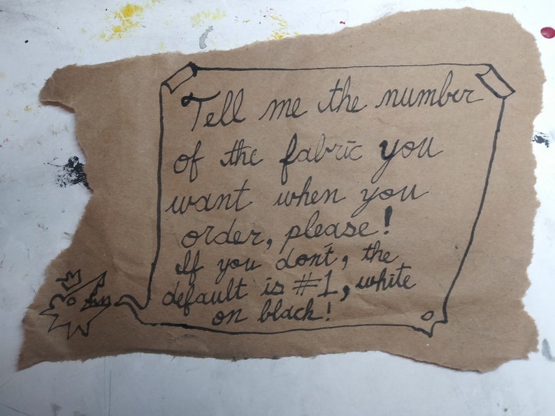 May include: A handwritten note on brown paper with the text: "Tell me the number of the fabric you want when you order, please! If you don't, the default is #1, white on black!"