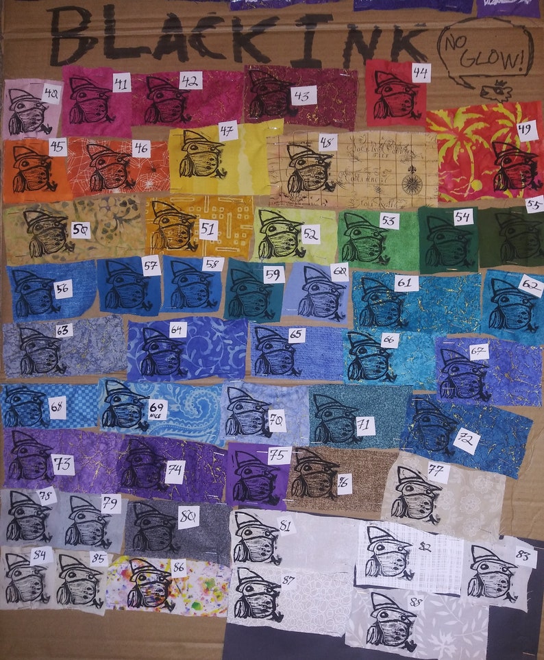 May include: A collection of 88 fabric squares with a black ink stamp of a frog wearing a hat. The fabric squares are arranged in rows and columns on a brown cardboard background. The fabric squares are in various colors and patterns. The text "BLACK INK NO GLOW!" is written at the top of the image.