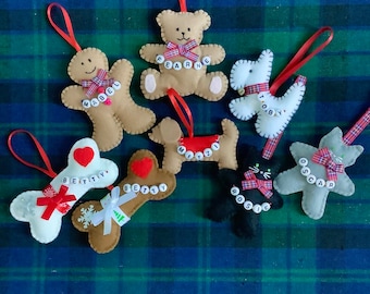 May include: Eight felt Christmas ornaments with different animal and gingerbread designs. Each ornament has a name spelled out with colorful letter beads. The ornaments are on a green and blue plaid fabric.