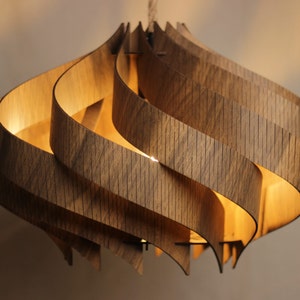 May include: A wooden pendant light fitting with a swirling, organic design. The light is made of multiple layers of wood that are curved and interlocked to create a unique and modern look.