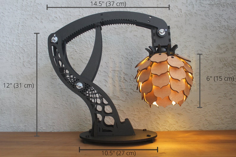 May include: A black and brown articulated lamp with a geometric base and a pineapple-shaped shade. The lamp is 14.5 inches tall, 12 inches wide, and 6 inches deep.