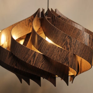 May include: A modern, wooden pendant light fixture with a swirling, organic design. The light is made of multiple layers of wood veneer, creating a unique and textured look.
