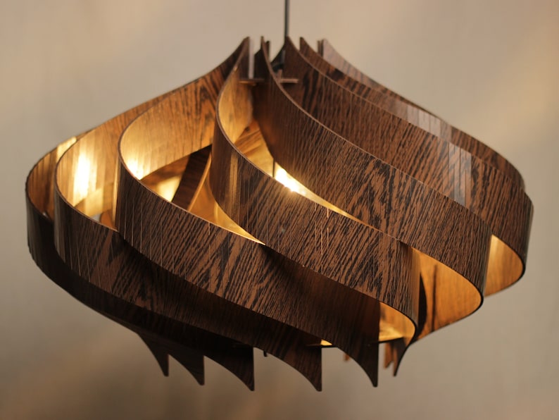 May include: A modern, wooden pendant light fixture with a swirling, organic design. The light is made of multiple layers of wood veneer, creating a unique and textured look.