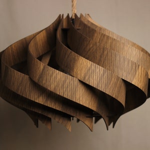 May include: A wooden pendant light fixture with a unique, swirling design. The light is made of multiple layers of wood that are interwoven to create a complex and intricate pattern.