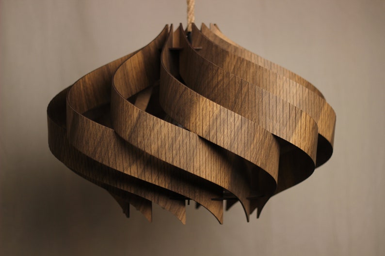 May include: A wooden pendant light fixture with a unique, swirling design. The light is made of multiple layers of wood that are interwoven to create a complex and intricate pattern.