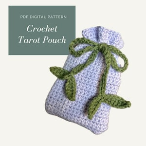 Puede incluir: Una bolsa de tarot de ganchillo lavanda con hojas de ganchillo verdes y cierre de cordón. La bolsa está etiquetada como "PDF Digital Pattern Crochet Tarot Pouch".