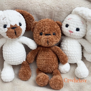 Könnte beinhalten: Drei handgefertigte Häkeltiere: ein weißer Hund mit braunen Akzenten, ein brauner Teddybär und ein weißes Häschen mit langen Ohren. Die Spielzeuge sind weich und kuschelig, perfekt für Kinder. Das Wort "Crochetce" ist orange geschrieben.
