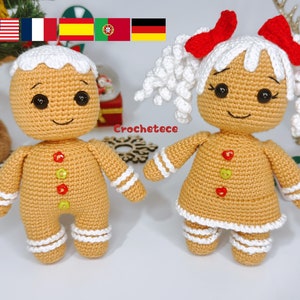 May include: Two crocheted gingerbread people, one with white hair and red bows, the other with brown icing on its head. Both have brown eyes, red smiles, and white icing accents. The gingerbread people are standing on a white surface.