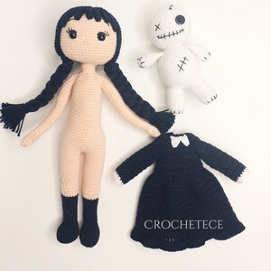 May include: Crocheted doll with black hair and a black dress, a white crocheted doll with black stitching, and a black dress with a white collar.