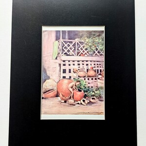 Könnte beinhalten: Ein gerahmter Druck mit einem Aquarellgemälde, das eine Person im Umgang mit Terrakottatöpfen zeigt. Die Szene spielt sich im Freien ab, mit einer Veranda und Grün in der Hintergrund. Das Kunstwerk ist in einem schwarzen Rahmen montiert.
