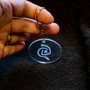 Roswell inspired crystal clear keychain with a frosted Antar symbol on. image 1