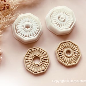 Puede incluir: Cuatro cortadores de galletas con forma de girasol en blanco y beige. Los cortadores tienen un diseño detallado de girasol con un agujero central. La imagen incluye flores secas y el aviso de copyright "Copyright © Babycutters 2025".