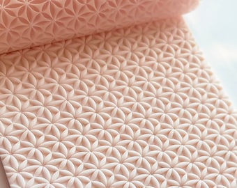 May include: A light pink rolling pin with a repeating floral pattern. The pin is partially rolled, showing the detailed design. The surface is clean and the colour is consistent throughout the product.