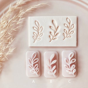 May include: A collection of leaf-shaped stamps and molds. The stamps are carved into a rectangular block, while the molds are in a rectangular shape with a raised leaf design. The color palette is soft, with a focus on neutral tones.