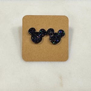 May include: A pair of black glitter stud earrings shaped like Mickey Mouse heads.
