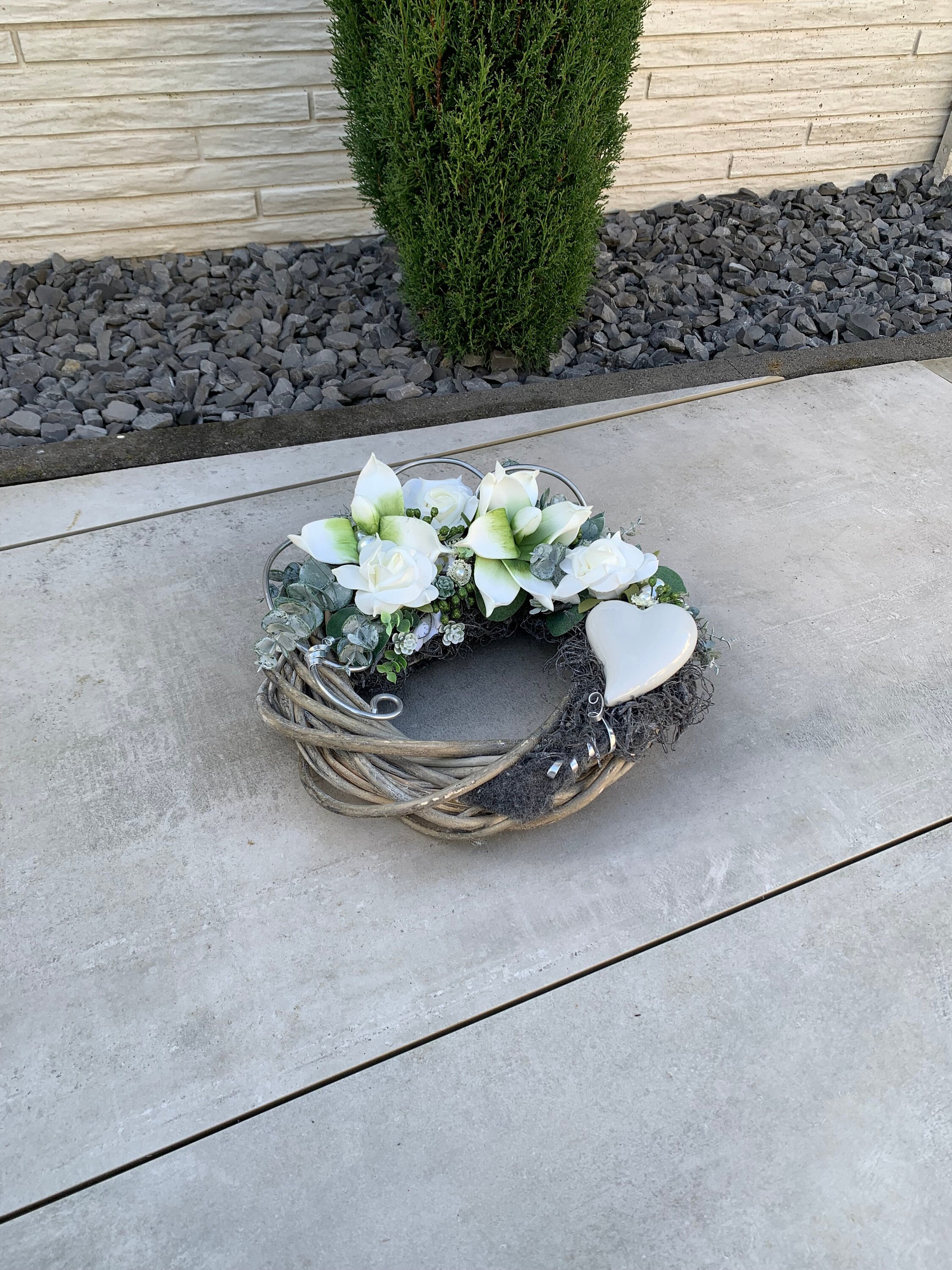 Grabschmuck zu Allerheiligen oder Gedenktag. Grabgesteck auf Rattankranz