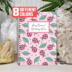 May include: A pink spiral notebook with a ladybug and leaf pattern. The notebook has a white label with the text "Any Name/Wording Here".