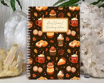 Może przedstawiać: Brązowy notes w spirali z jesiennym wzorem. Okładka przedstawia powtarzający się wzór z latte z przyprawą dyniową, babeczkami, ciastem i jesiennymi liśćmi. Na okładce nadrukowany jest tekst "Any Name/Wording Here".