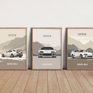 May include: Three framed prints of white Toyota Supra MK4 cars against a beige mountain landscape. Each print features the text "TOYOTA" and "SUPRA MK4".