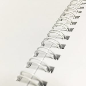 May include: A white spiral bound notebook with a close-up view of the binding.