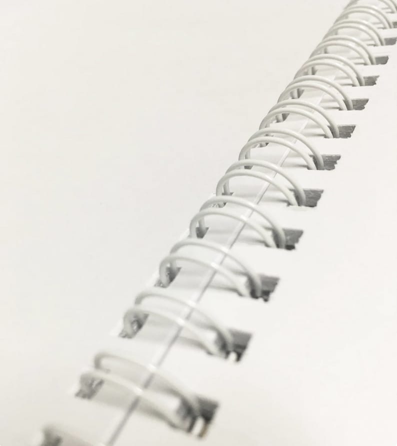 May include: A white spiral bound notebook with a close-up view of the binding.